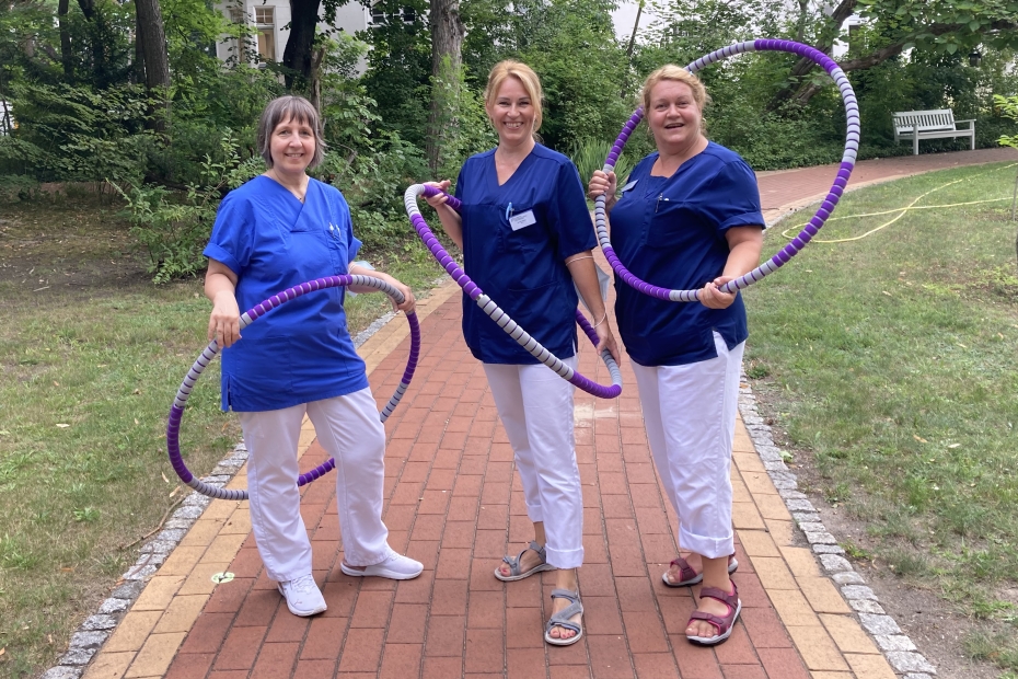Drei Frauen in Pflegekleidung mit Hoolahoop-Reifen vor dem Krankenhaus