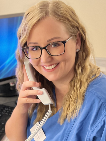 Teamomat: Pflegefachkraft mit Brille an der Rezeption am Telefon