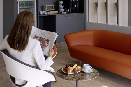 Teamomat: Junge Frau macht Pause mit Zeitung im Aufenthaltsraum