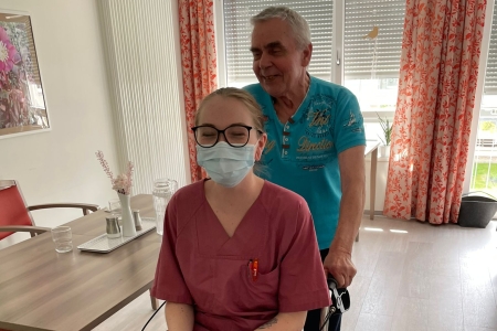 Teamomat: Pflegekraft wird von Bewohner auf Rollator aus Zimmer geschoben