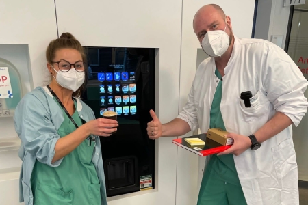 Teamomat: Zwei Kolleg*innen vor Kaffeeautomat