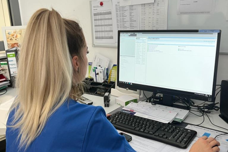 Teamomat: Weibliche Pflegefachkraft sitzt vor PC