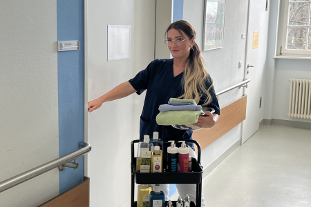 Teamomat: Weibliche Pflegefachkraft vor Tür zum Patientenzimmer