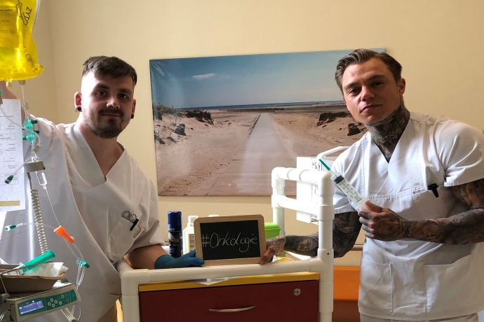 Zwei Pfleger halten Tafel mit Aufschrift "Onkologie"