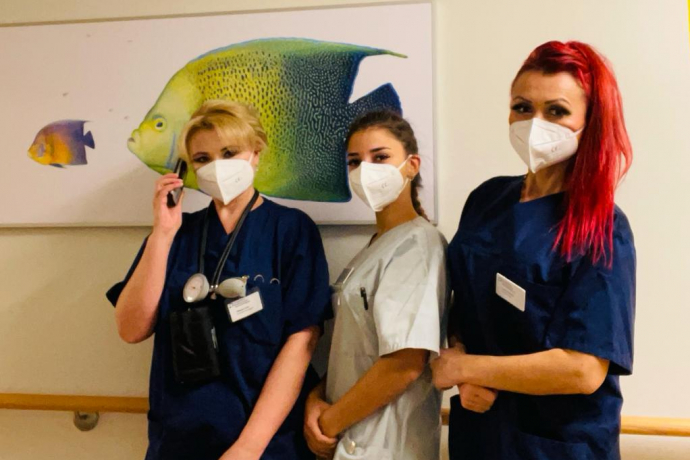 Teamomat: Drei Kolleginnen stehen vor Bild mit Fisch an der Wand