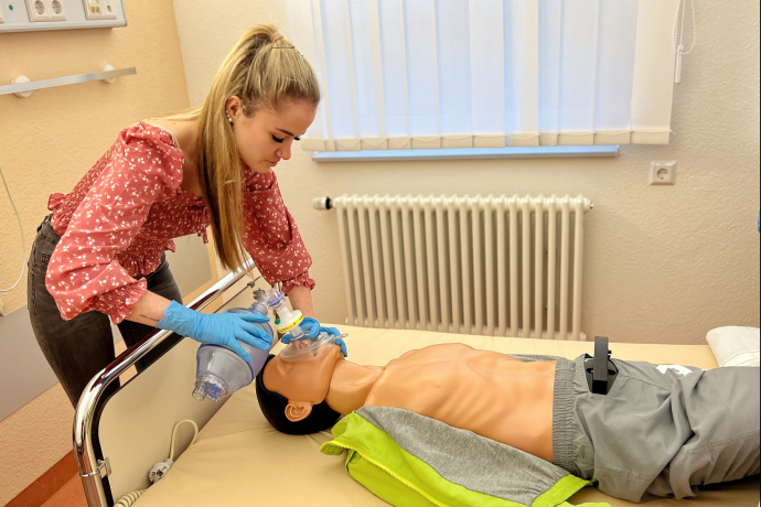 Teamomat: Junge Frau übt an Reanimationspuppe