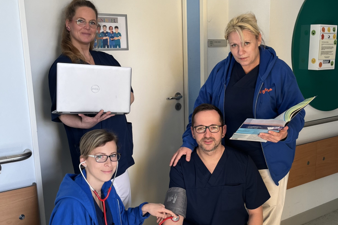 Teamomat: Vier Pflegefachkräfte vor Tür zum Dienstzimmer